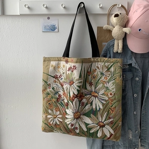 Close-up of floral print canvas tote bag with daisy pattern and black nylon straps