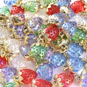 Macro shot of colorful resin strawberry charms with gold leaf clasps for DIY jewelry