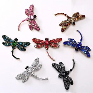 Detail view of large dragonfly brooches featuring colorful crystals and vintage metal base