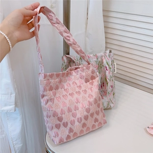 Detail of pink heart jacquard and floral fabric textures on a mini handheld tote bag