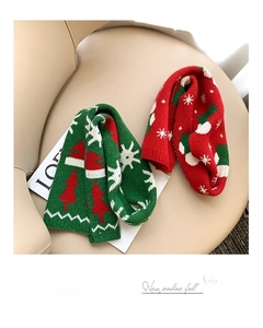 Detail of festive knitted kids' scarves featuring Christmas tree and snowflake patterns