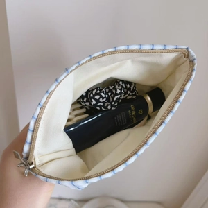 Detail showing the inner lining and capacity of the blue striped cotton handbag with items