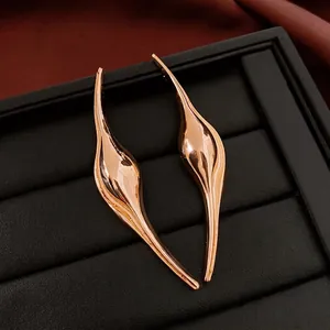 Minimalist curved teardrop earrings in polished rose gold on black textured display
