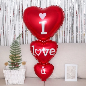 Three-tier red heart foil balloons with I Love U print on a minimalist sofa