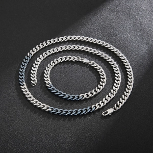 Detail shot of silver and blue gradient Cuban link chain set on textured background