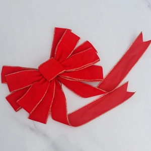 Close-up of red velvet Christmas bow with gold glitter edges on marble surface