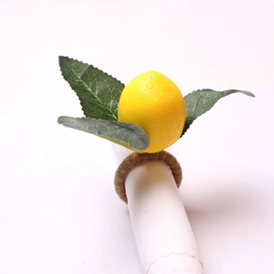 Lifelike artificial lemon napkin ring with green leaves and brown twine on white napkin
