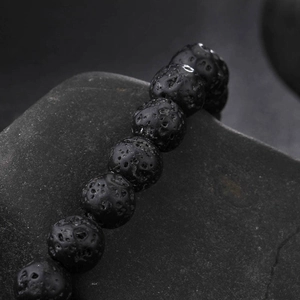 Macro detail of natural black porous lava stone beads on a stainless steel bracelet