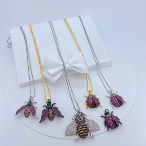Close-up of insect pendants in gold and silver set with colorful zircon gemstones