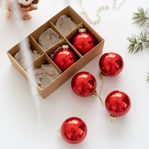 Red Christmas ball ornaments set in brown kraft box with pine needles and festive decor