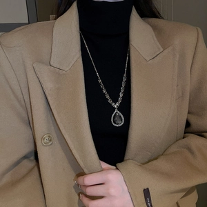 Détail d'un collier en V argenté avec pendentif en cristal sur un mannequin