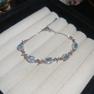 Silver bracelet with blue oval gemstones and bow charms on velvet jewelry tray