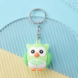 Detail of green and white silicone owl keychain with silver ring on striped background