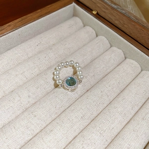 Dettaglio di anello di perle vintage con gemma turchese e aureola di cristalli lucidi