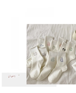 Close-up of white cotton crew socks featuring various cartoon animal embroidery details
