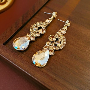 Dettaglio di orecchini vintage dorati con cristalli color ambra su scatola di legno