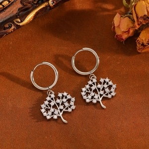 Detail of silver tree of life hoop earrings with sparkling crystals on a vintage surface