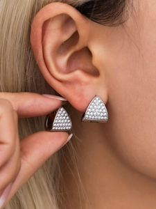 Macro shot of silver triangle earrings with micro-pave white cubic zirconia on ear