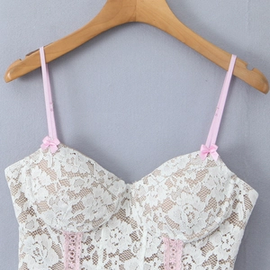 White lace camisole top with pink bow detail and thin straps on a wooden hanger
