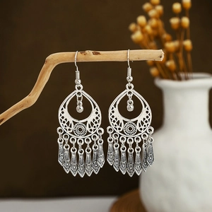 Detailed view of silver bohemian tassel earrings hanging on a natural wooden branch