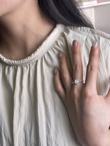 Detail view of a 925 sterling silver ring with oval white gemstone on a finger