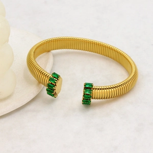 Dettaglio del bracciale rigido dorato a torsione a C con pietre di zircone verde rettangolari