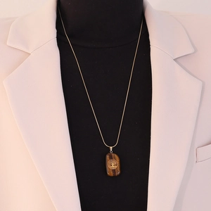 Tiger eye stone tree of life pendant necklace shown on a black turtleneck sweater