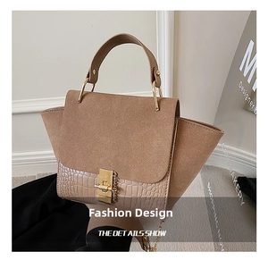 Detailed shot of khaki wing bag featuring crocodile texture and gold metal turn-lock