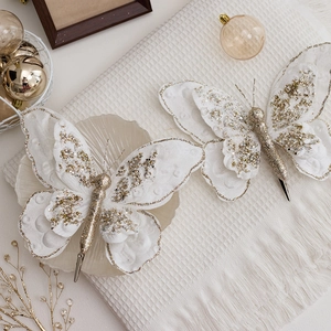 Elegant white and gold glitter butterfly Christmas tree ornament clips on a fabric surface