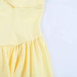 Close-up of the waist stitching and delicate pleated texture on a light yellow mini dress