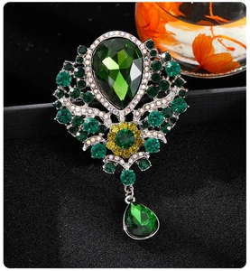 Detailed close-up of a green teardrop crystal brooch with intricate rhinestone inlay