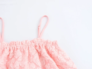 Dettaglio del tessuto goffrato rosa con scollatura elastica a pieghe sull'abito dolce