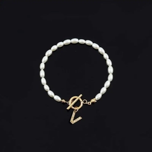 Elegant pearl bracelet featuring a gold T-bar clasp and a sparkling crystal letter V charm