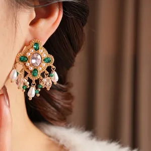 Vintage gold earrings with pink gemstones, green rhomboids and pearl tassels on a model