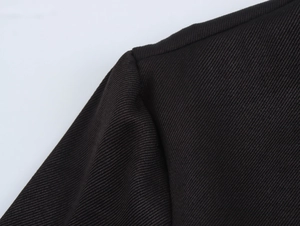 Détail macro des coutures d'épaule et texture du tissu noir de la robe à volants