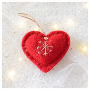 Detail of red felt heart ornament with snowflake embroidery and wood button for Christmas