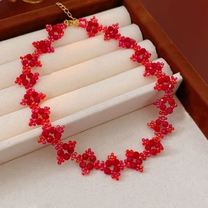 Detailed macro view of handmade red beaded choker with gold lobster clasp and extension chain
