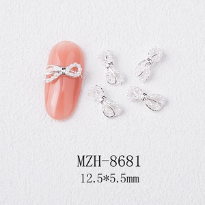 Macro shot of 3D alloy bow nail charm with white pearls on pink gradient manicure