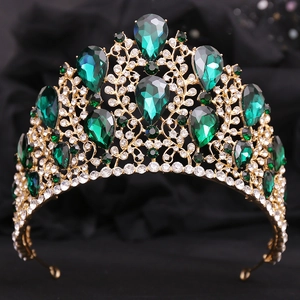 Close-up of golden baroque crown featuring pear-shaped emeralds and clear crystals
