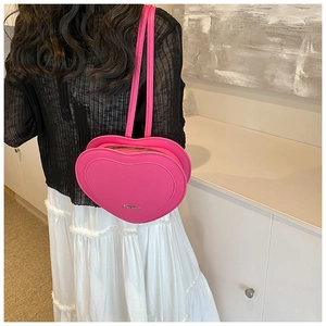 Rear view of a model wearing a bright pink heart-shaped backpack in smooth PU leather