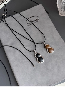 Close-up of hulu gourd pendants with black and brown leather inlay on metal frame