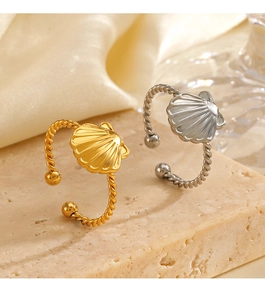 Detail view of 18K gold and silver shell rings with twisted band on stone texture