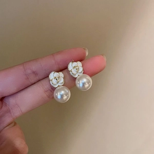 Detailed close-up showing the intricate white camellia design and large hanging pearls