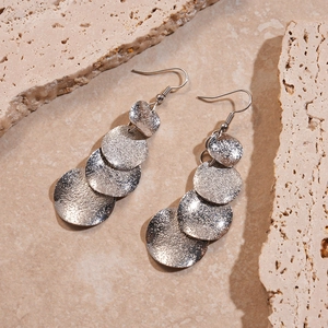 Vue détaillée des boucles d'oreilles géométriques argentées au fini mat texturé