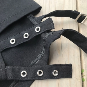 Dettaglio ravvicinato di pantaloncini neri elasticizzati con occhielli e fibbie in metallo