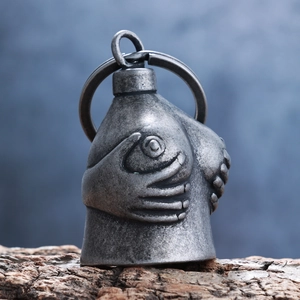 Macro detail of vintage motorcycle guardian bell pendant with textured hand sculpture