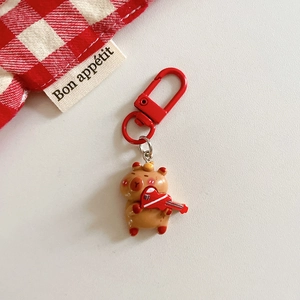 Close-up of a resin Capybara keychain holding a red guitar with a red D-ring clip