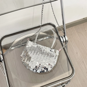 Detail of silver sequin shoulder bag with metal chain on minimalist interior background
