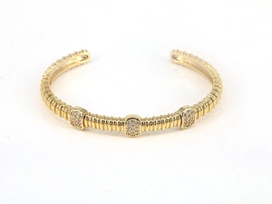 Detailed close-up of gold-plated cuff bracelet with screw texture and zircon inlay