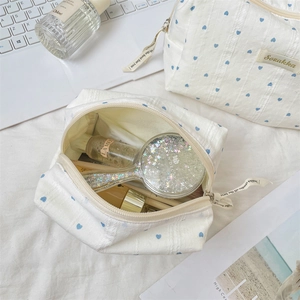 Detail of striped heart makeup bag showing open and closed views with lifestyle props